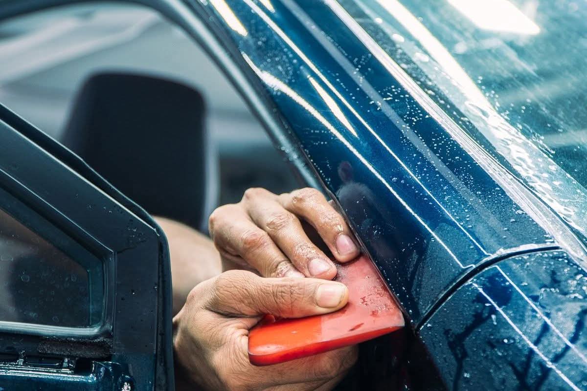 Technician applying paint protection film to a car