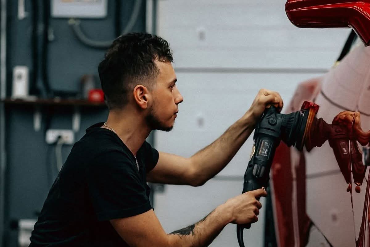 Technician detailing and polishing a car in a garage