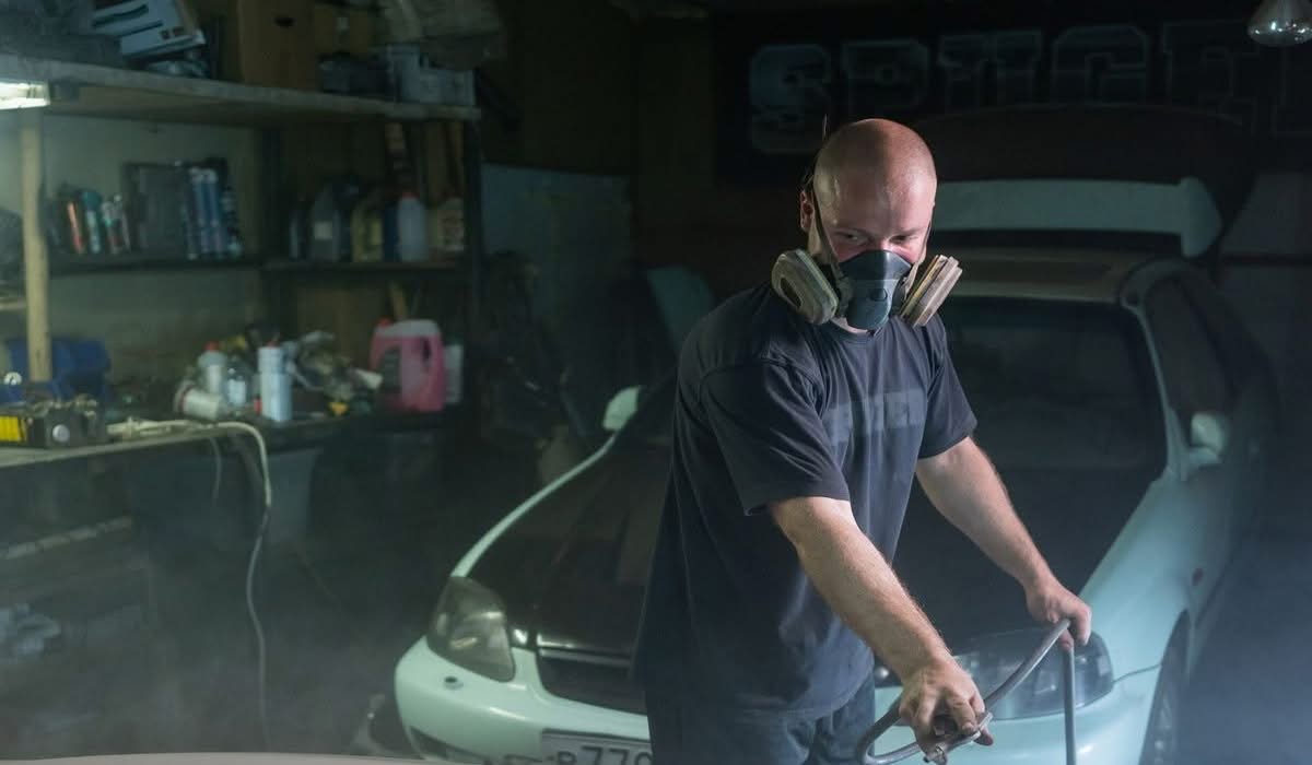 Paint Touch-Up vs. Full Respray: What's Right for Your Car? 3 Technician spray painting a car panel in a workshop