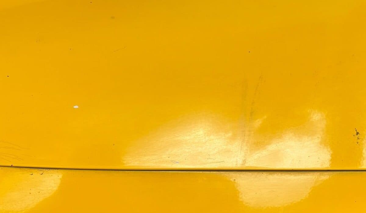 Common Types of Car Paint Damage and How to Fix Them 2 Close-up of light surface scratches and swirl marks on a cars glossy yellow paint