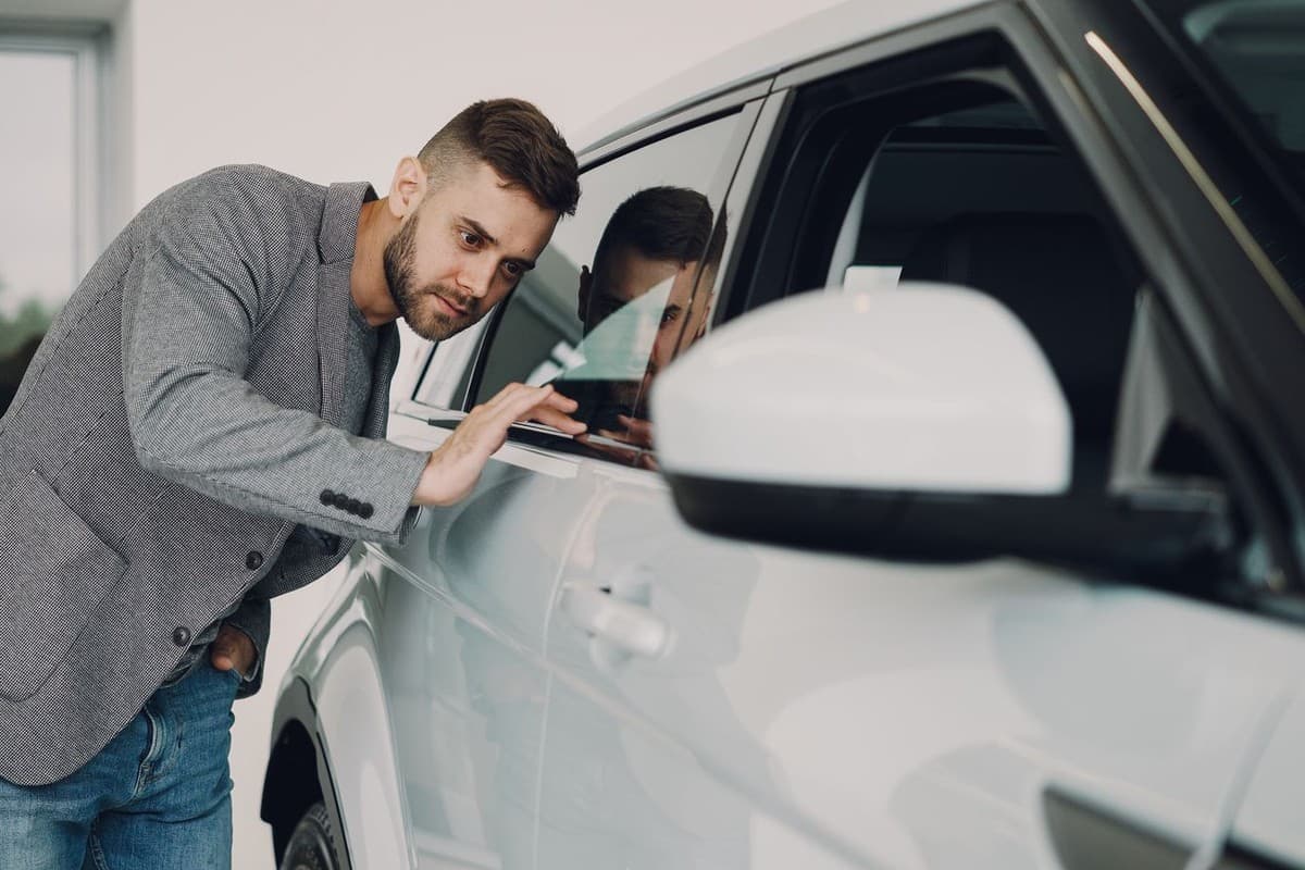 How Paint Touch-Ups Protect Your Car's Resale Value 5 Prospective buyer closely inspecting a cars paint and body panel before purchase