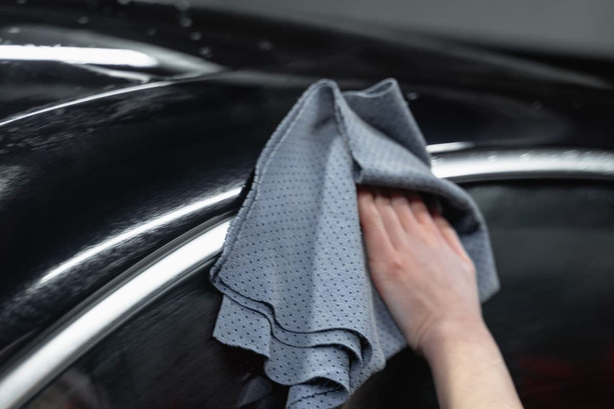 Why Experience Matters in Auto Paint Restoration 1 Hand carefully hand-wiping a finished car panel with a microfiber cloth after paint restoration work