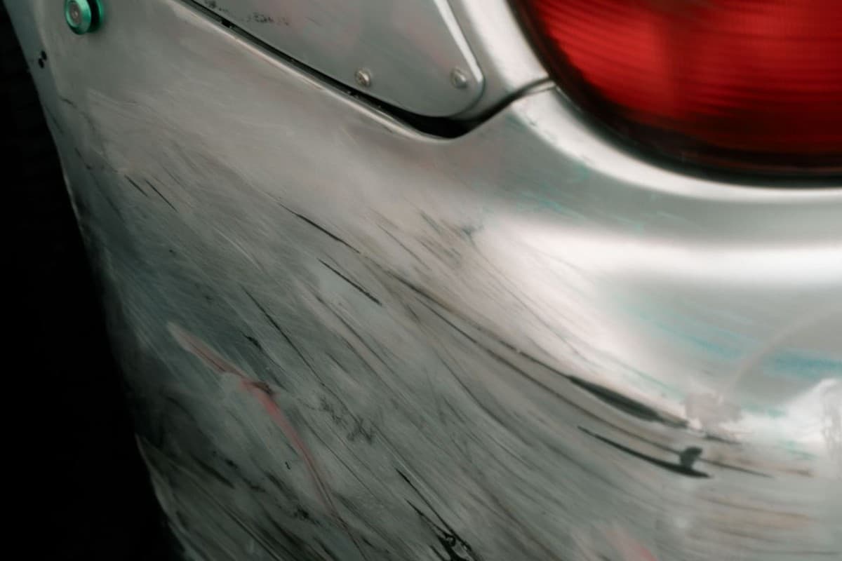 Close-up of scuff and paint transfer marks on a car bumper corner near the taillight