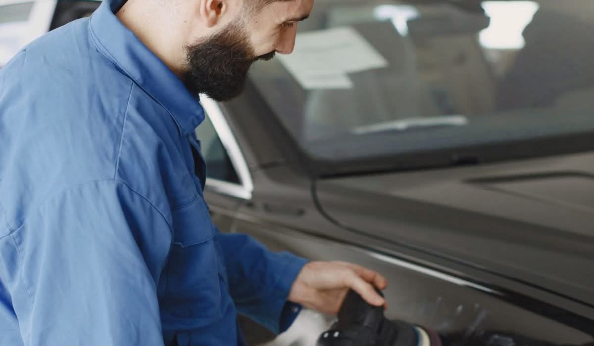 Technician polishing a car body panel in a workshop