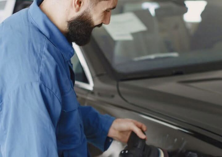 Technician polishing a car body panel in a workshop