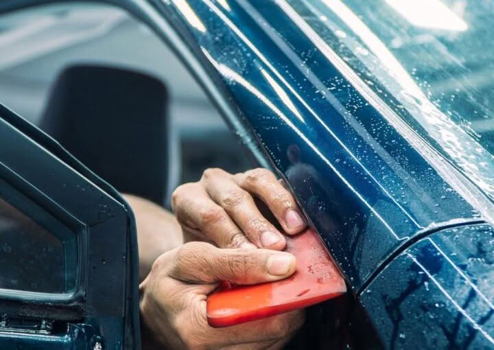 Technician applying paint protection film to a car