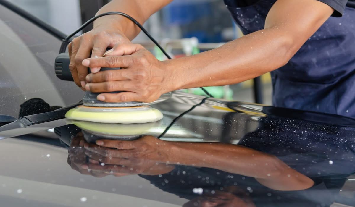 Hands using a polishing tool on a car surface