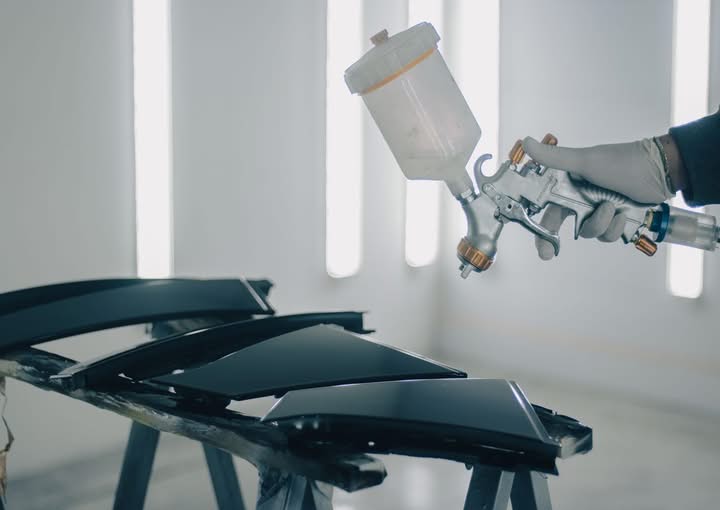 Close-up of a technician painting car body parts