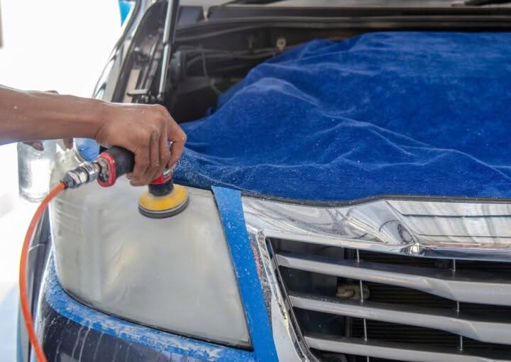 Technician polishing a foggy car headlight during restoration