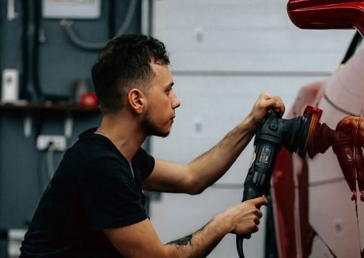 Technician detailing and polishing a car in a garage