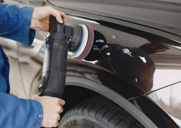 Hands using a polishing machine on a car's painted surface